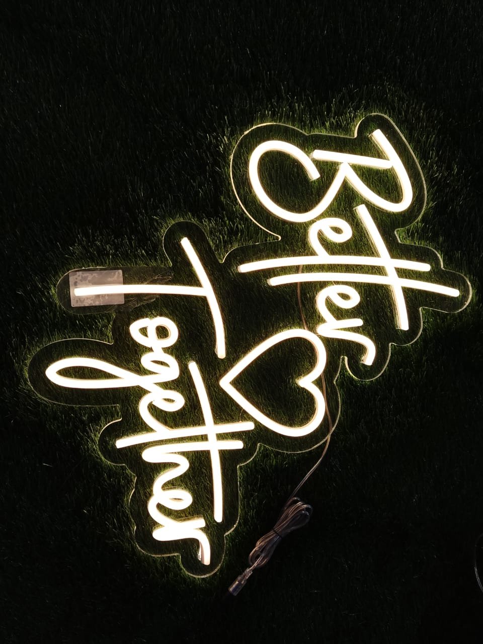 Off-white neon sign reading "Better Together" in cursive lettering.