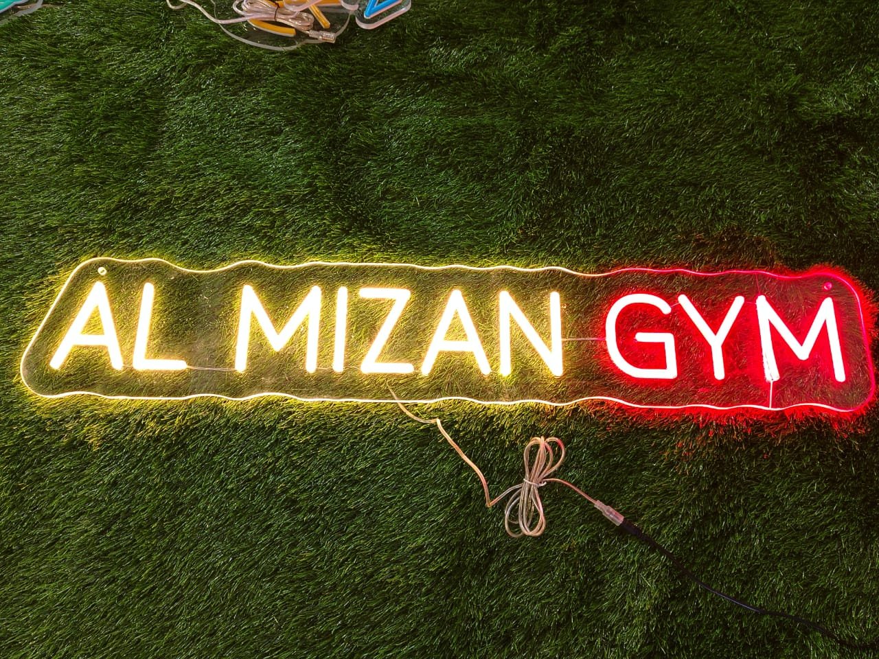 White neon sign displaying a custom gym name in strong, bold lettering