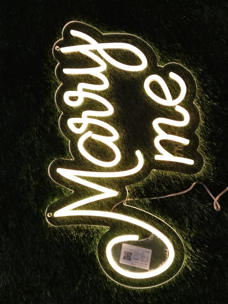 Neon sign reading "Marry Me" in glowing warm light, perfect for proposals and engagements.