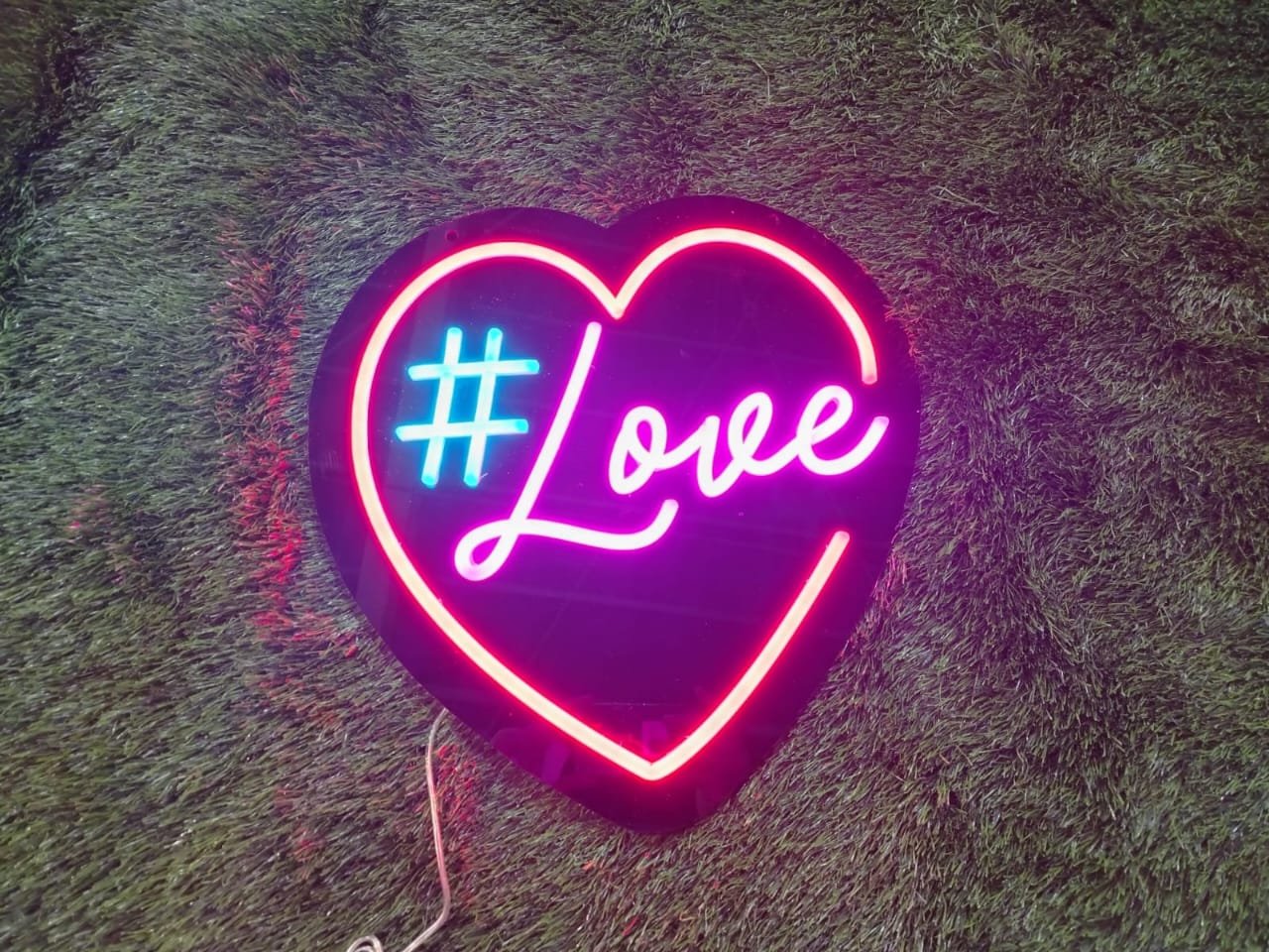 Neon sign with the word "Love" and a hashtag symbol inside a glowing heart outline.